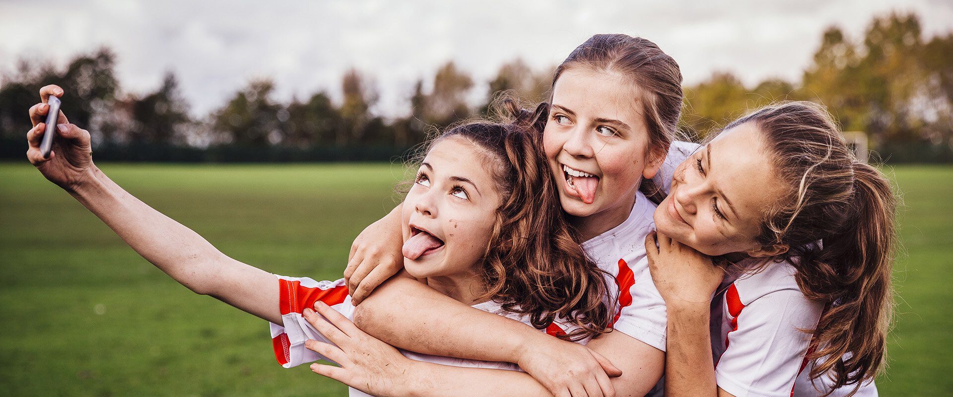 site blog api - three young girls taking a selfie after a game of fotball